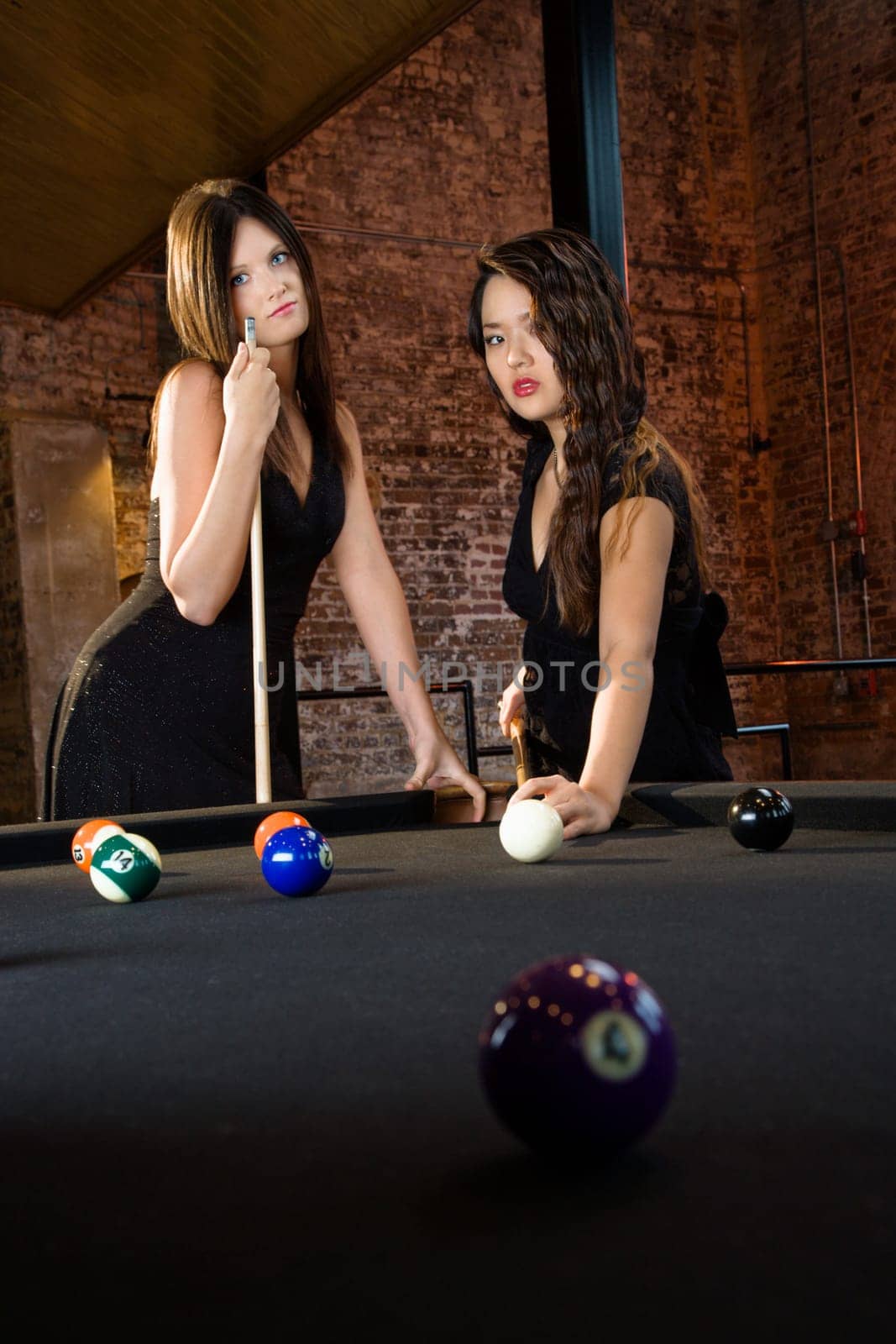 Two attractive young women playing billiard game.