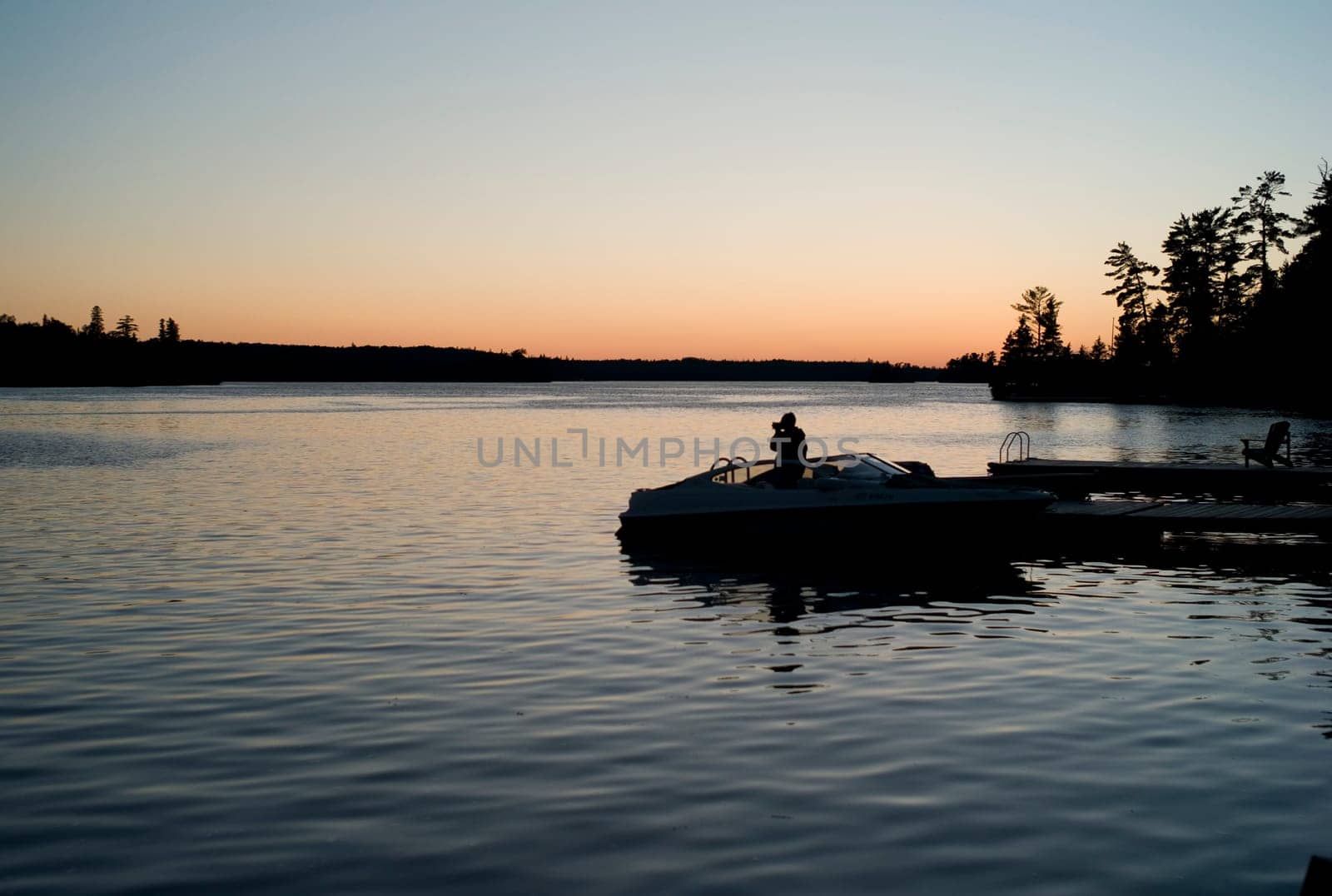 Boat by dock at sunset, Lake of the Woods, Ontario, Canada