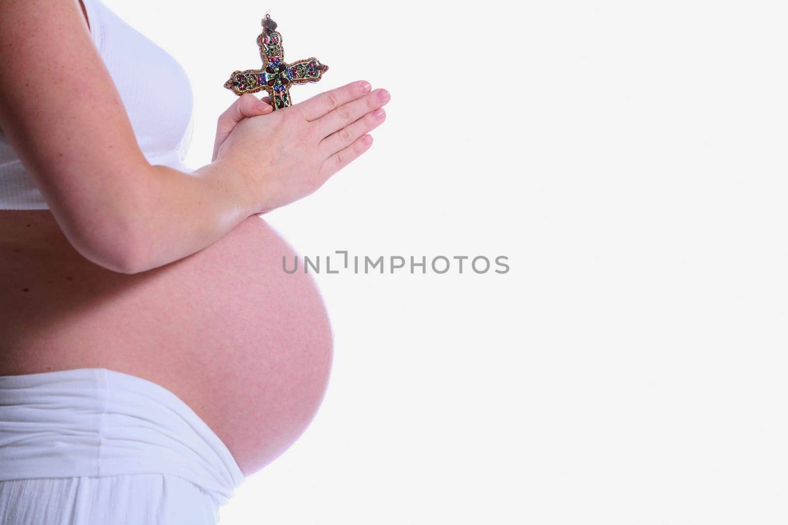 Pregnant woman praying with crucifix
