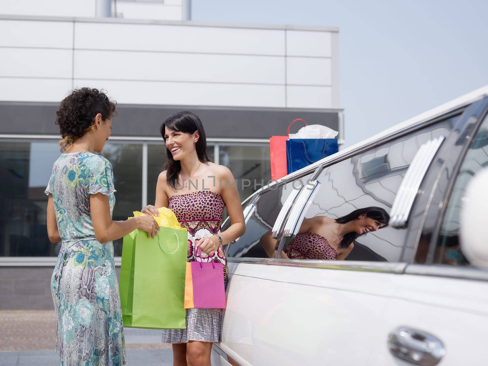 friends with shopping bags and limousine