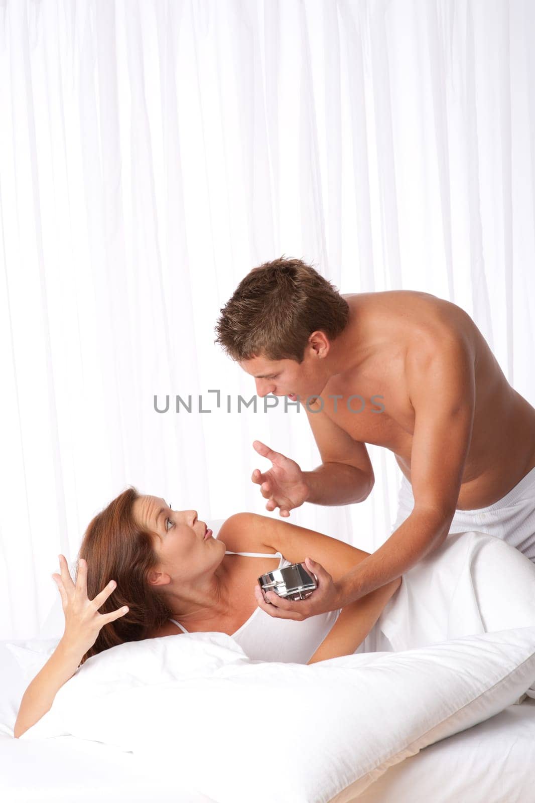 Young couple sleep in, argue in bed
