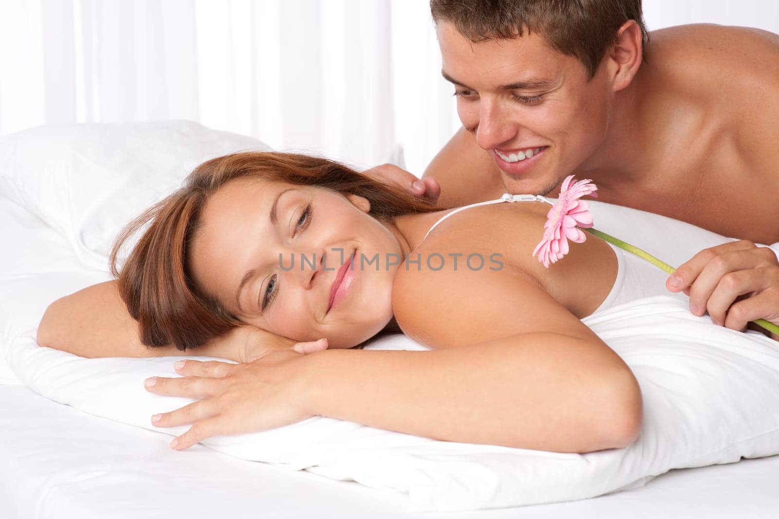 Honeymoon - Young couple embrace in bed