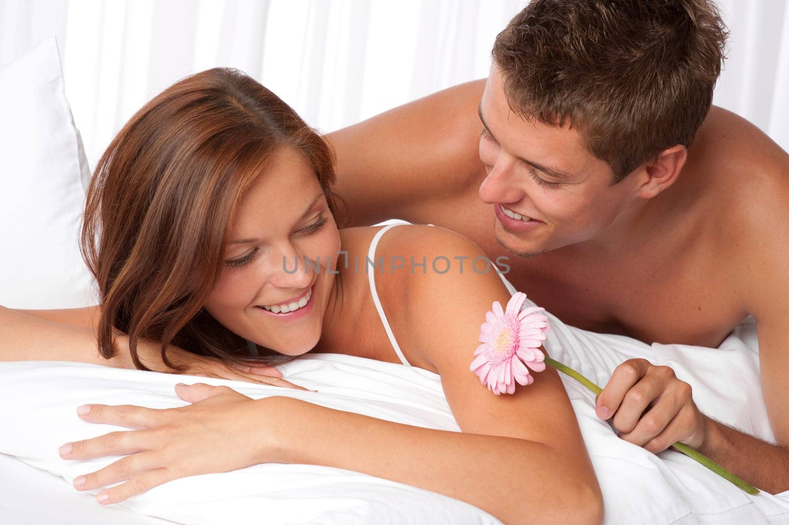 Honeymoon - Young couple embrace in bed