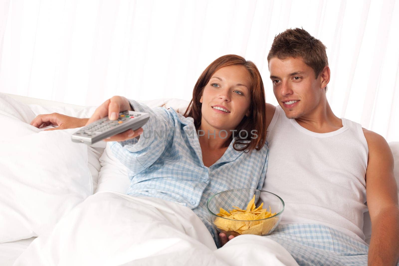 Couple lying in bed watching television