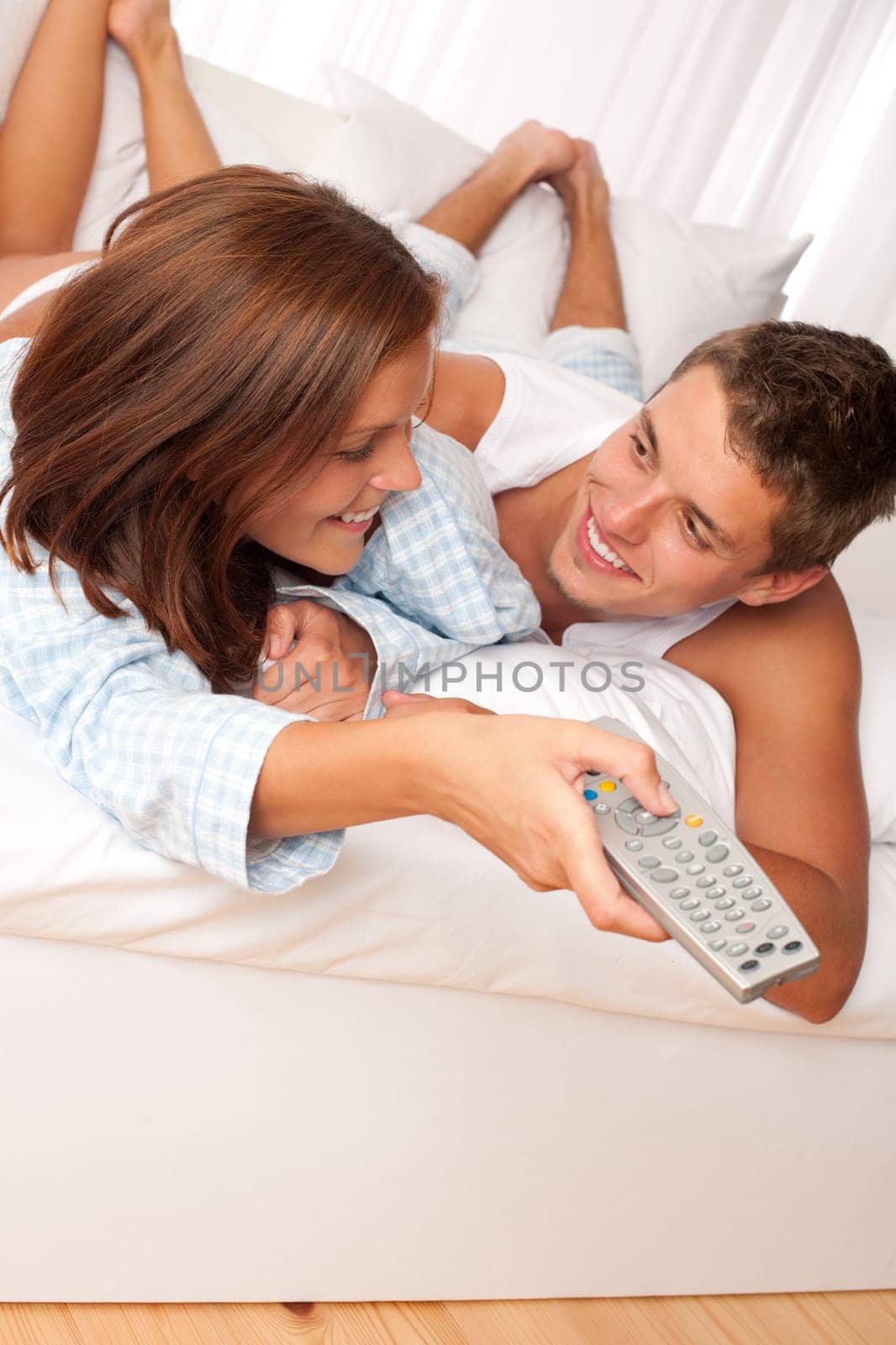 Young couple enjoy watching TV in bed