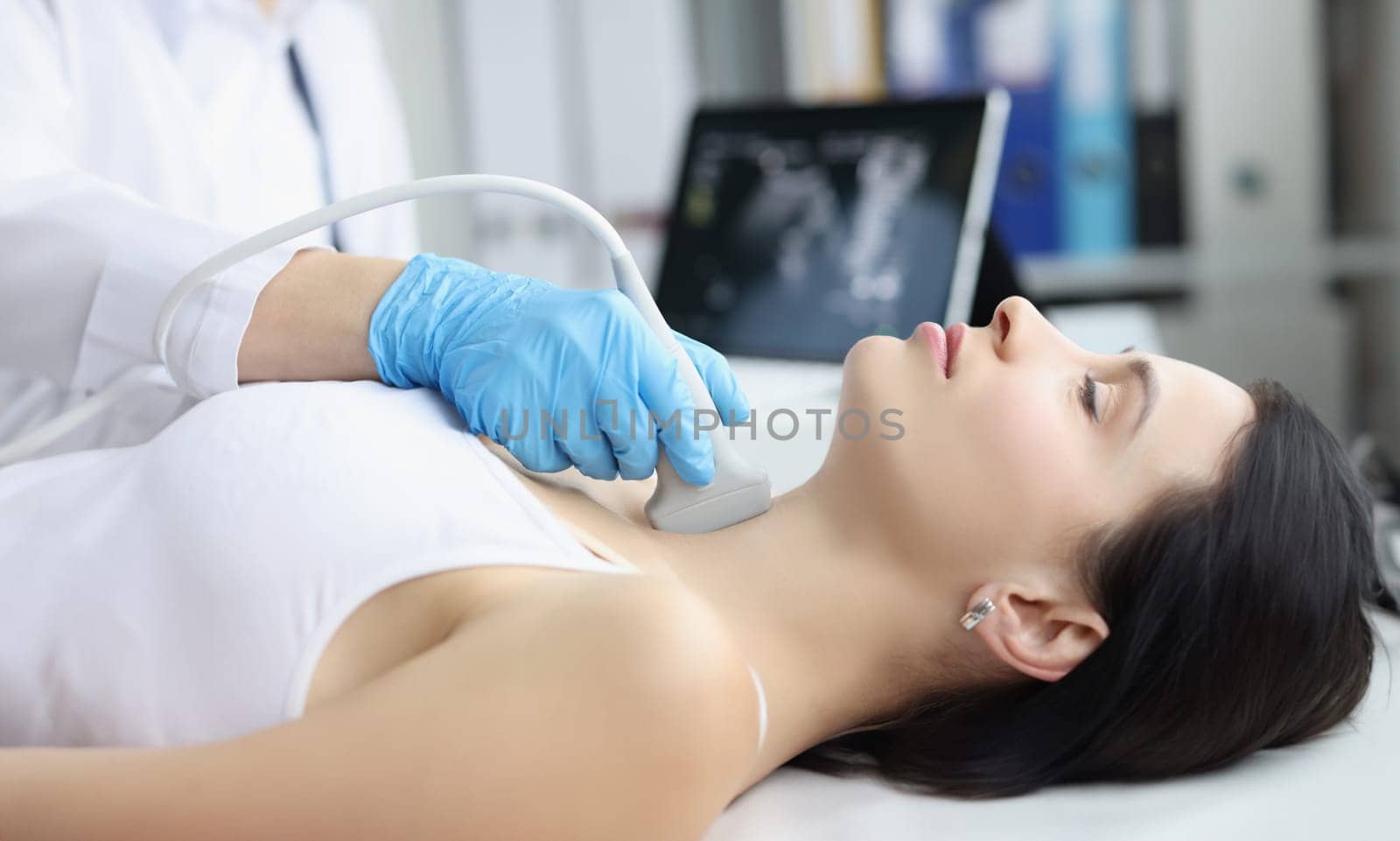 Portrait of ultrasound scanning diagnostic of woman thyroid gland in clinic, doctor runs ultrasound sensor over patients neck with gel. Diagnostics concept