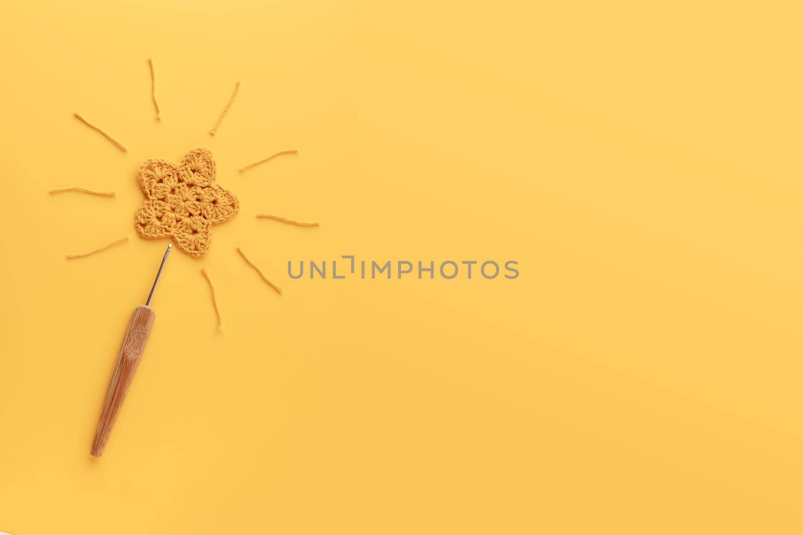 Magic wand - The yellow crocheted star on a yellow background with copy space