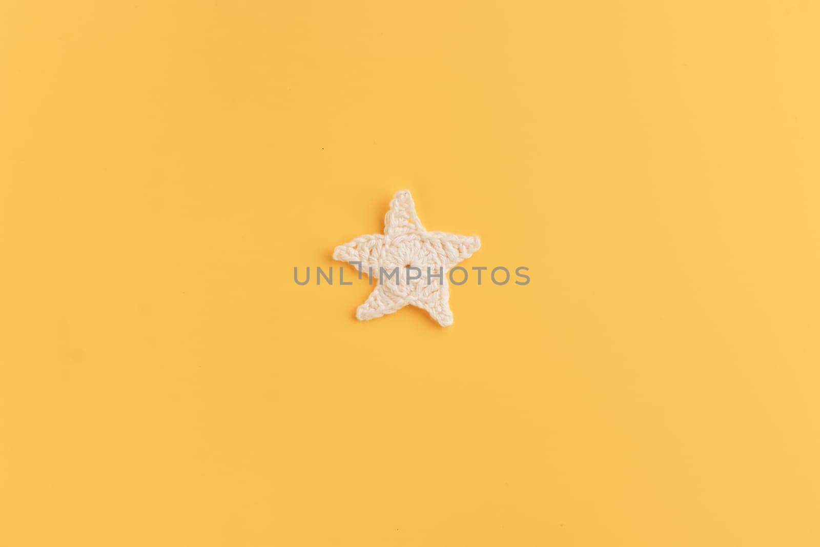 The white and yellow  crocheted star on a bright background with copy space / pattern by Gudzar