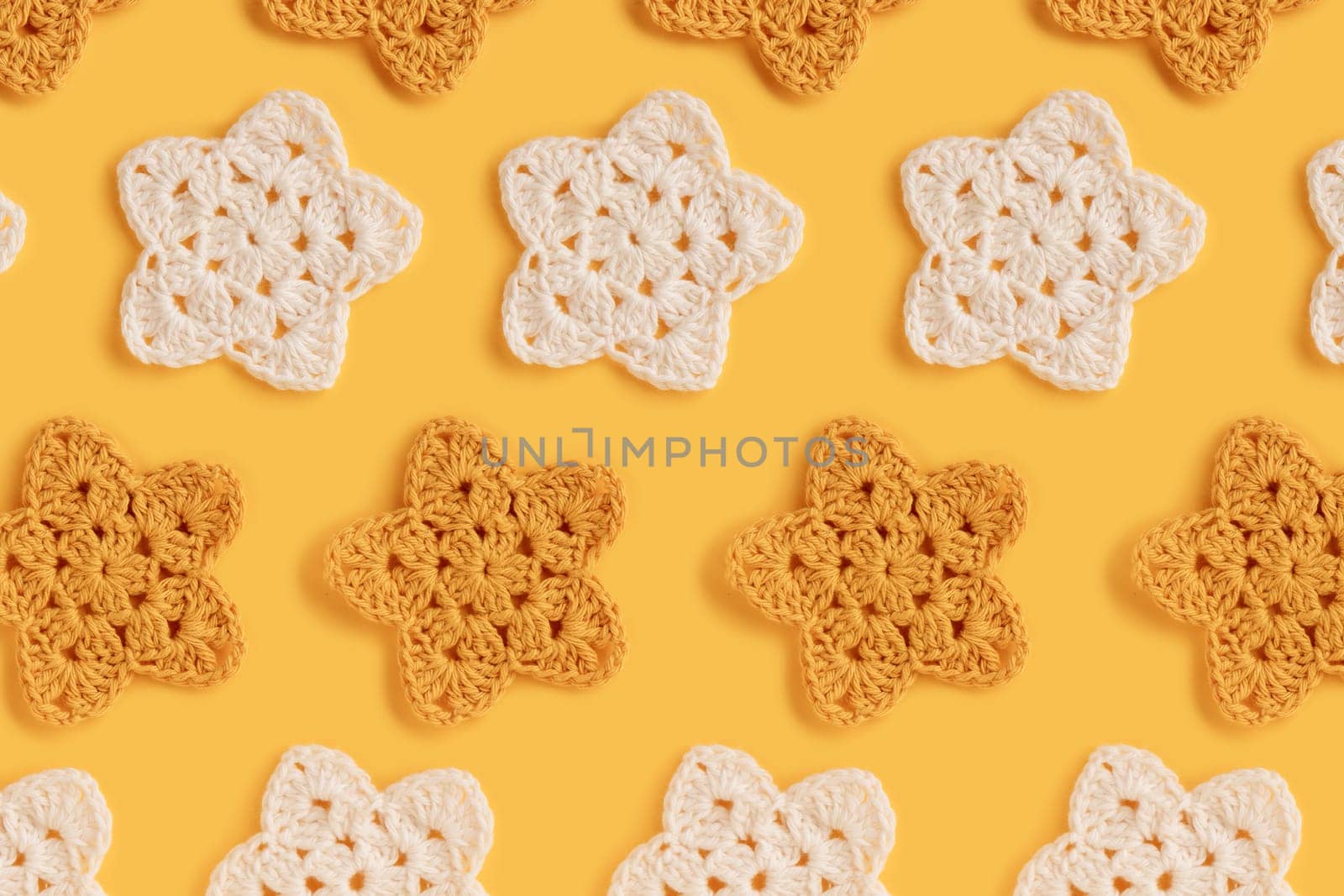 White and yellow crocheted stars pattern on a yellow background