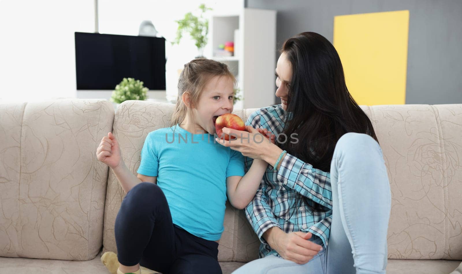 Portrait of mother feeding daughter with apple fruit, add vitaminized product to eating. Mother daughter time, food, diet, quality time, parenthood concept
