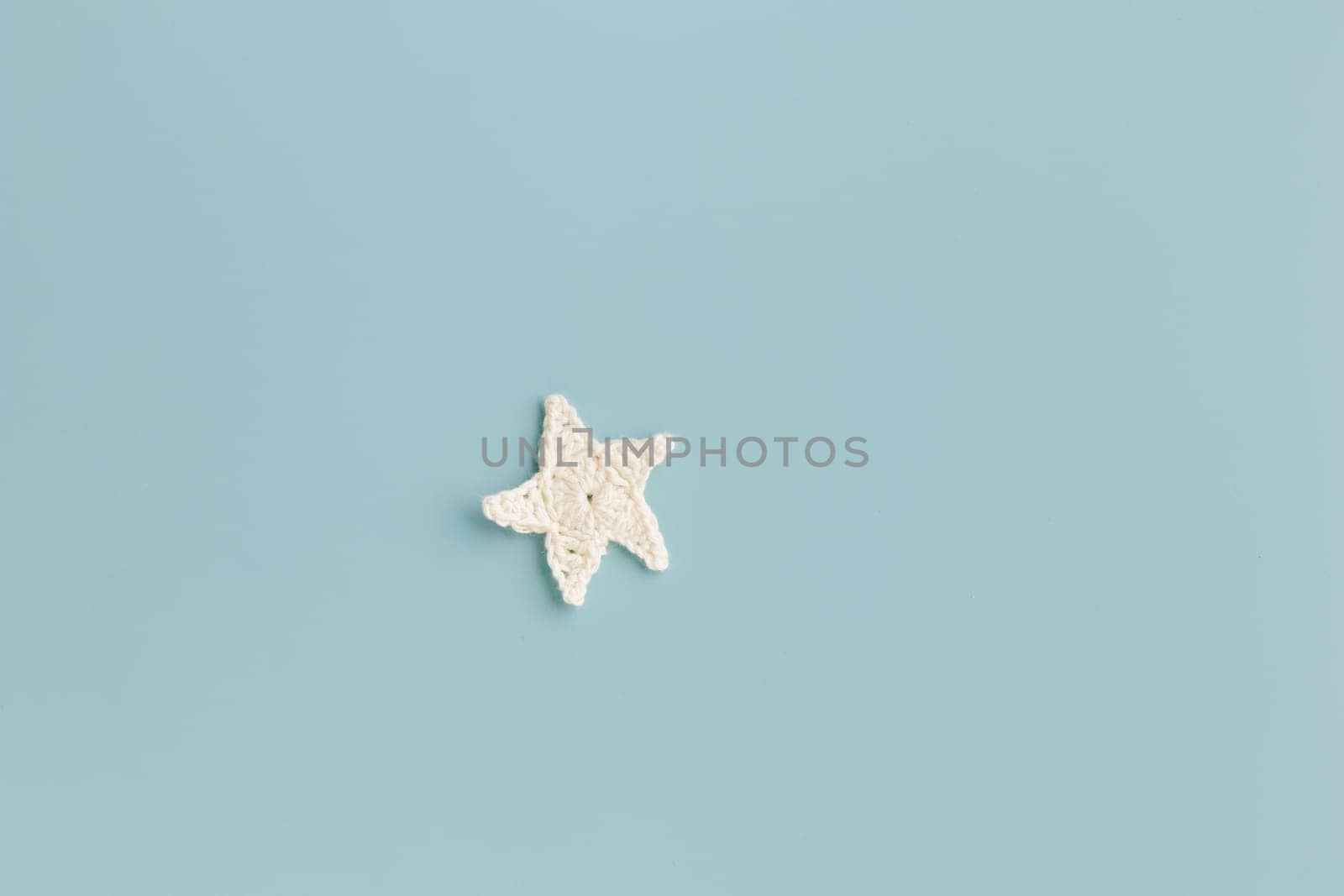 The white and yellow  crocheted star on a bright background with copy space / pattern
