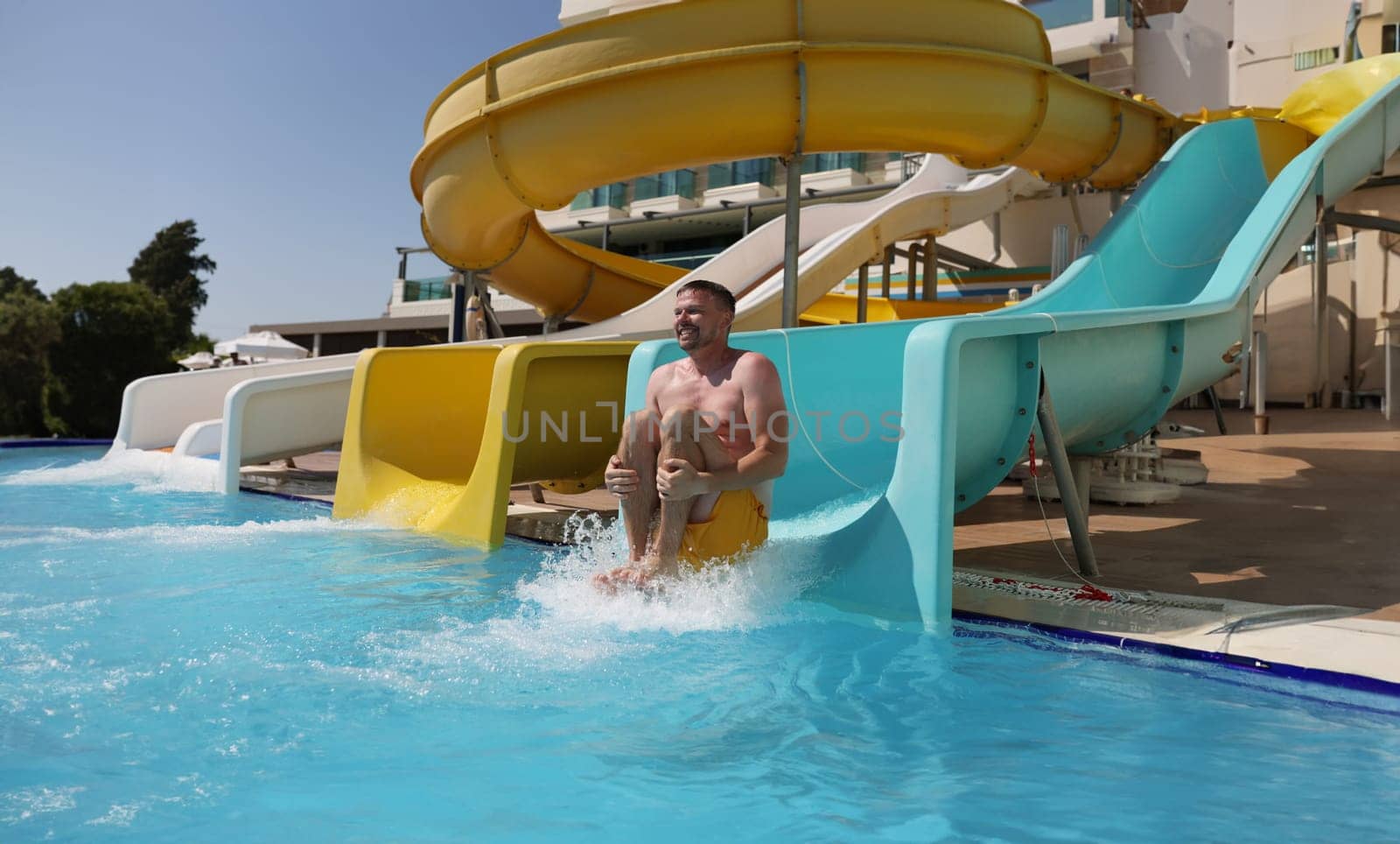 Middle aged man having fun, sliding at water park, summer vacation by kuprevich