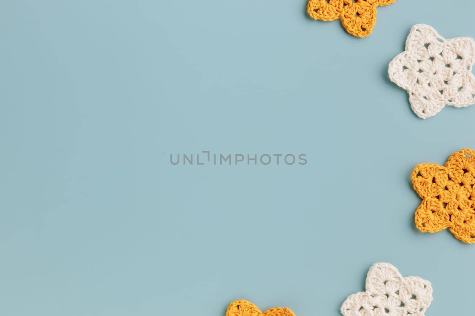 The white and yellow crocheted stars frame on a blue background with copy space