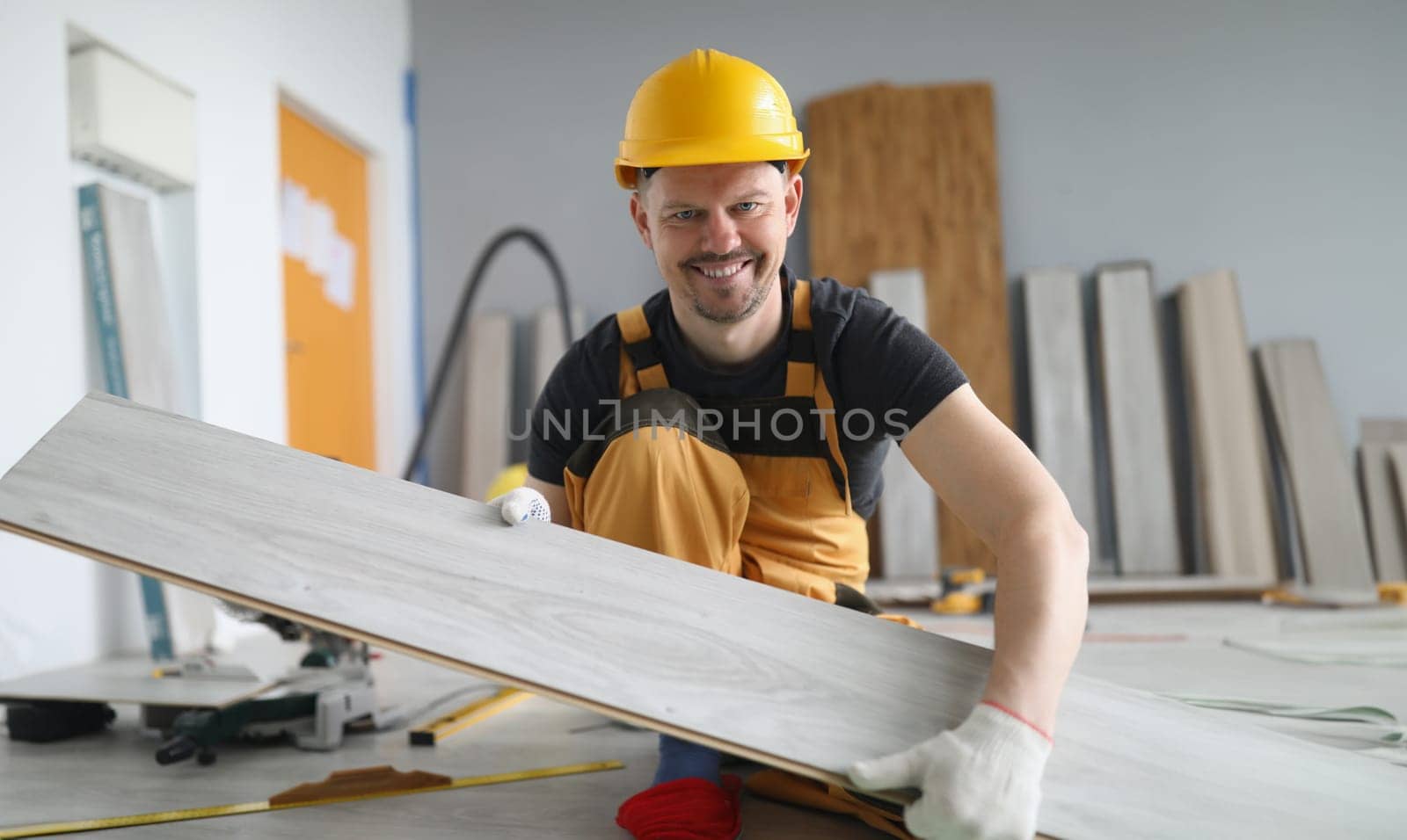 Portrait of qualified carpenter man carry wooden plank on working project, energetic worker in yellow uniform, renovation, construction site, fix concept