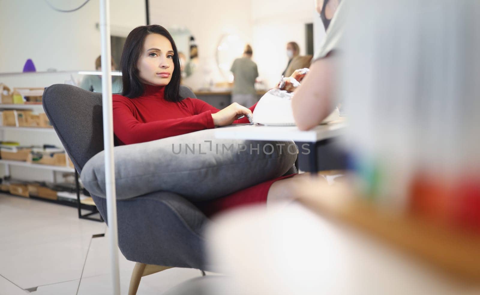 Bored lady client on manicure and pedicure appointment in beauty salon by kuprevich