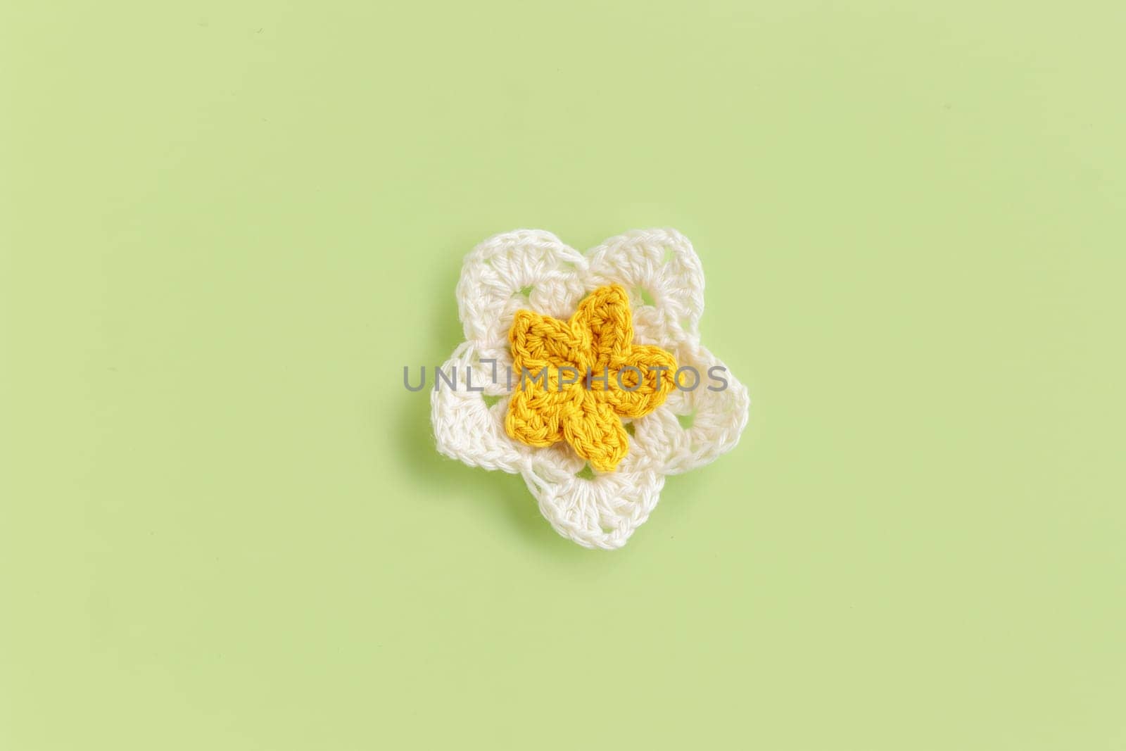 Yellow crocheted flower on a green background