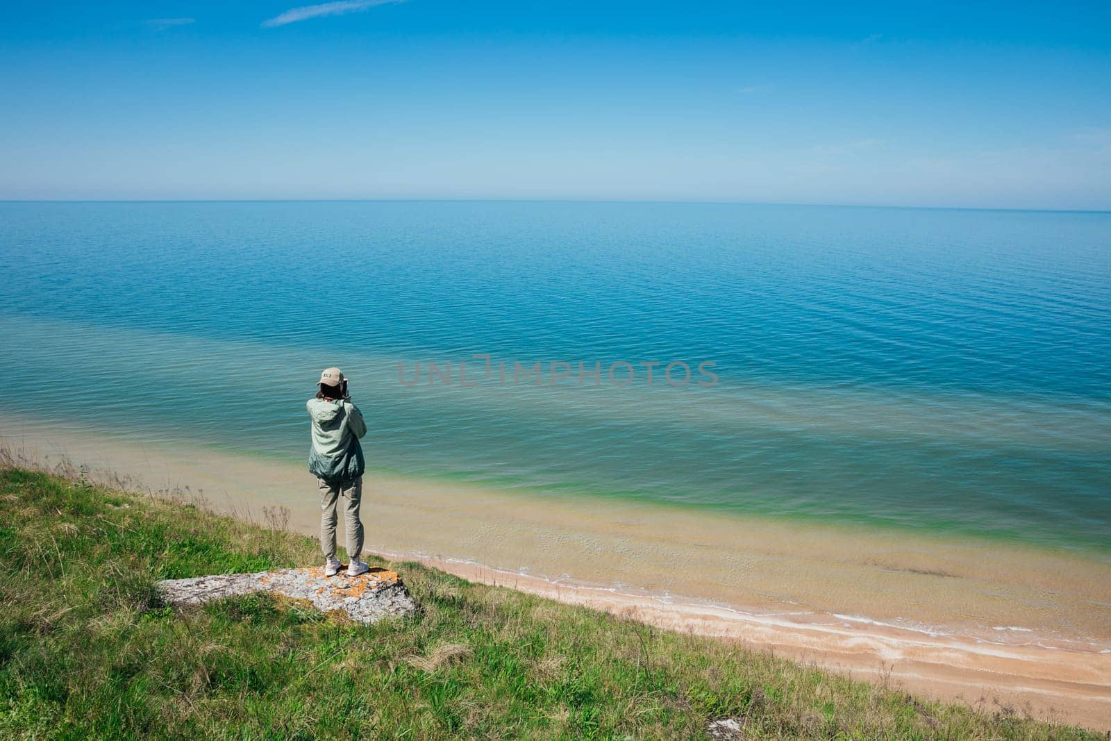 A woman stands on a mountain and looks out over the sea nature travel hiking by Simakov
