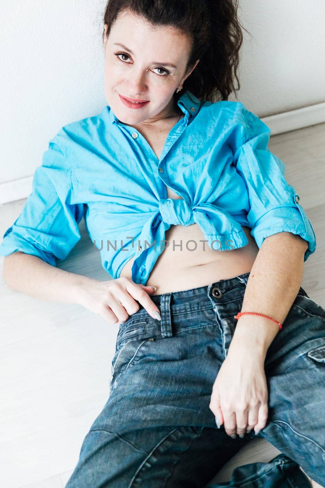 woman in a blue shirt lies on the floor in a bright room