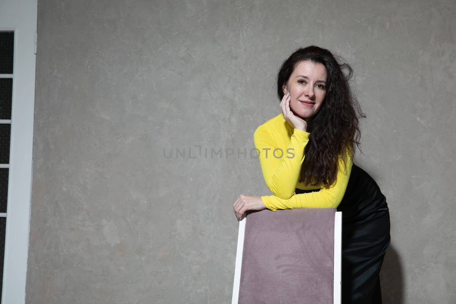a beautiful woman stands by a pink chair in the office by Simakov