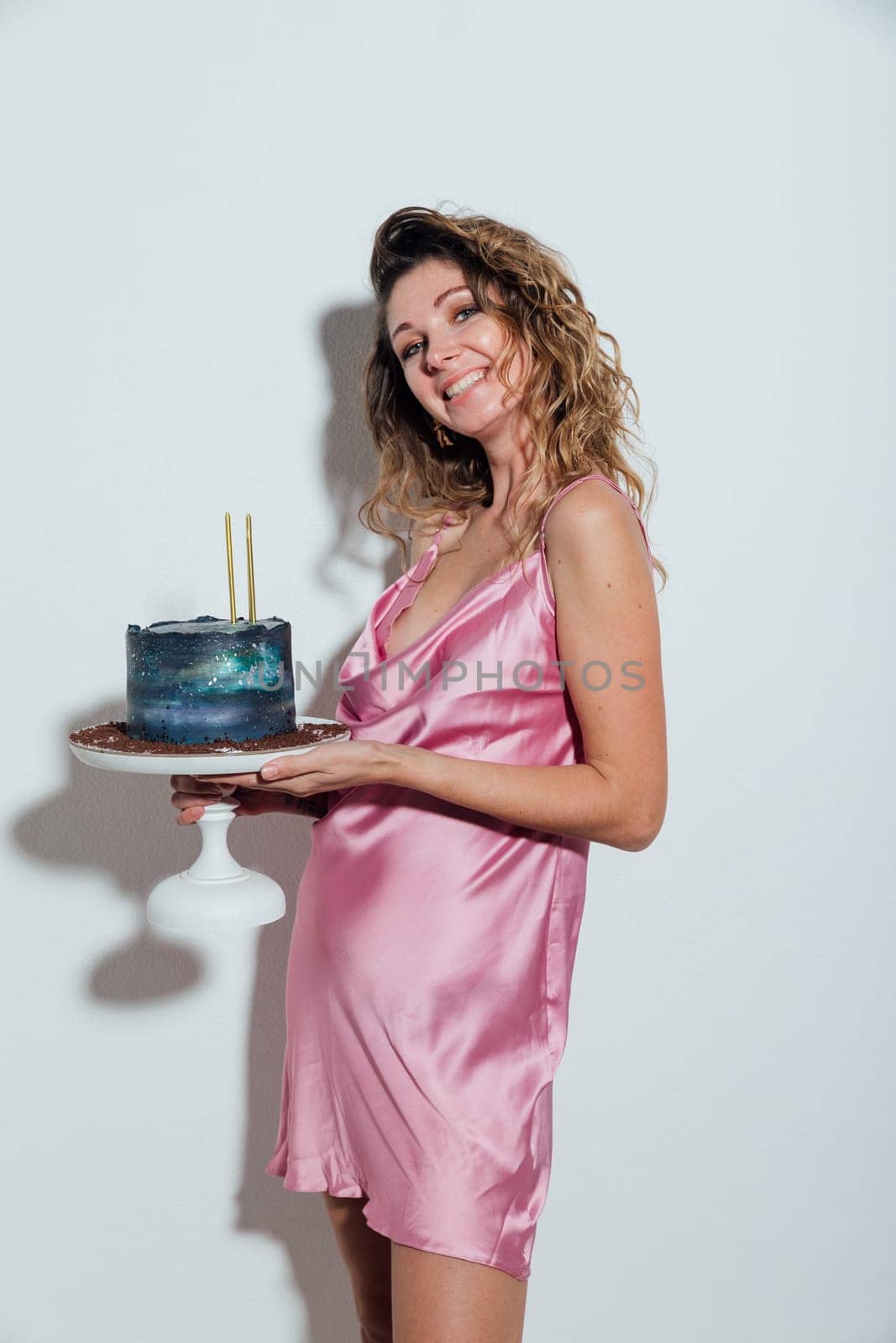 a woman in an elegant pink dress stands in a stone with a cake