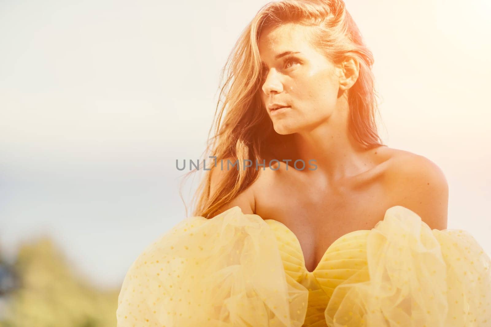 portrait of a beautiful young woman with brown hair in a gorgeous yellow dress looks into the distance