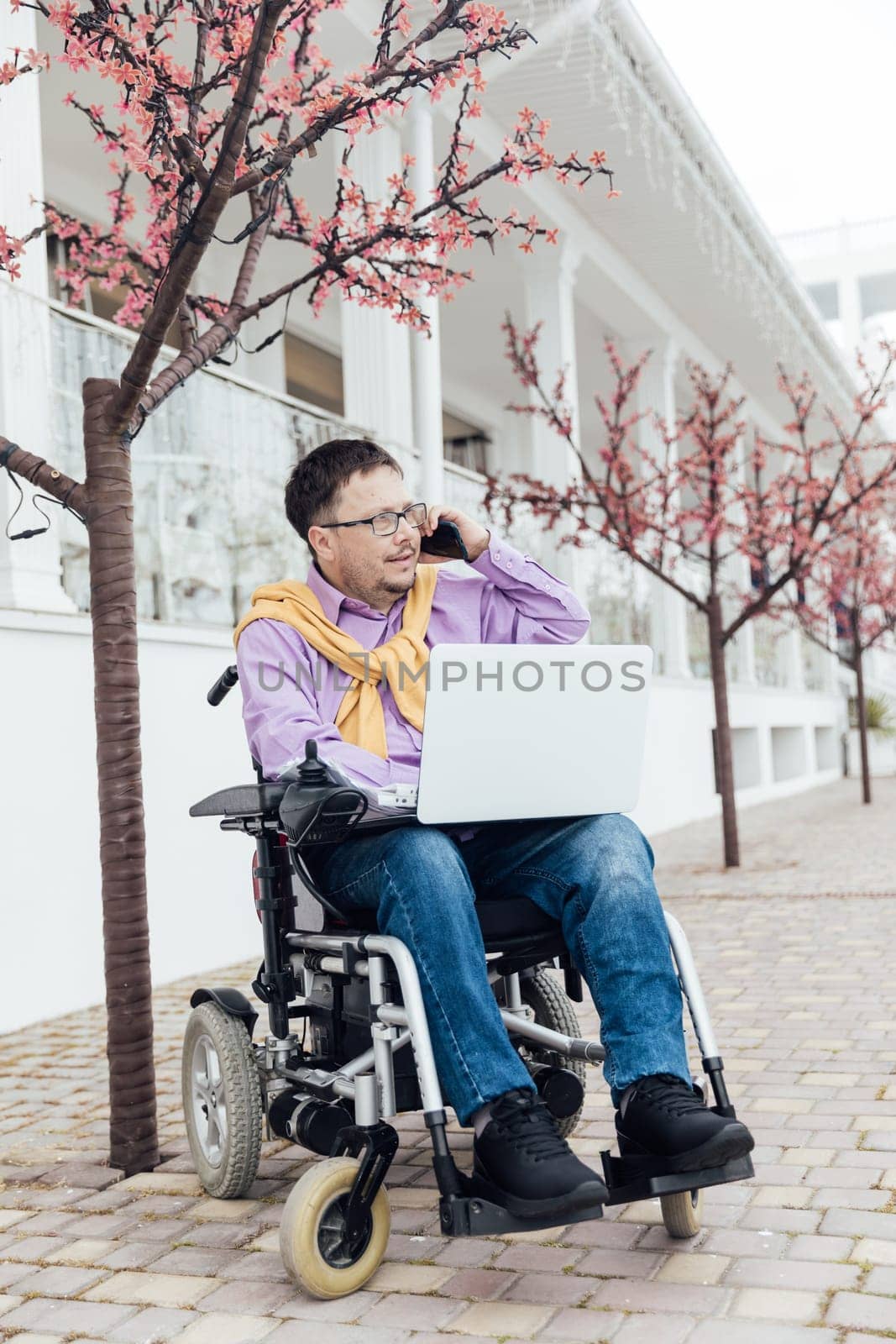 a special person with disabilities with a laptop talking on the phone in the park