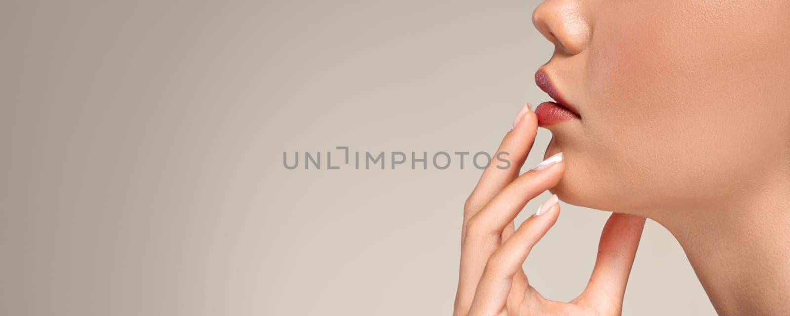 Calm european young woman with perfect skin touching hands to red lips, isolated on gray studio background, cropped, close up. Beauty care, nude makeup, moisturizing, panorama