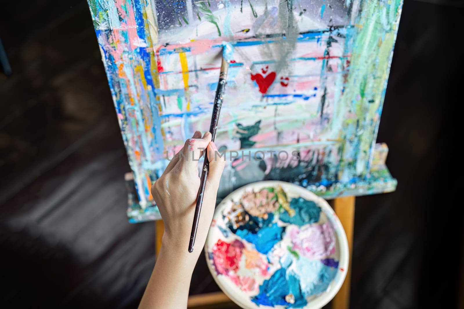 Female artist hold color palette and paintbrush for painting during hobby workshop.