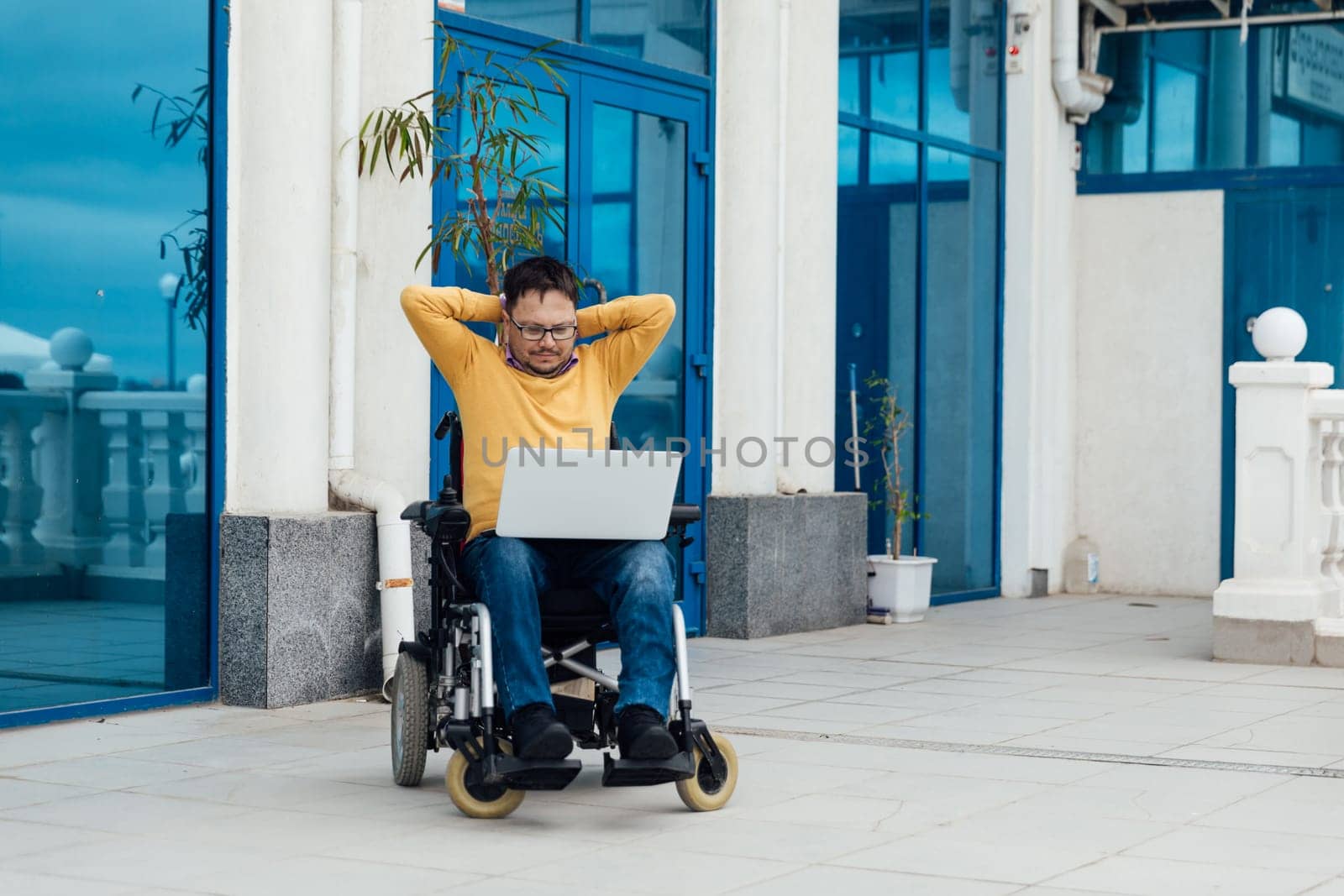 a special person with disabilities with a laptop talking on the phone by Simakov