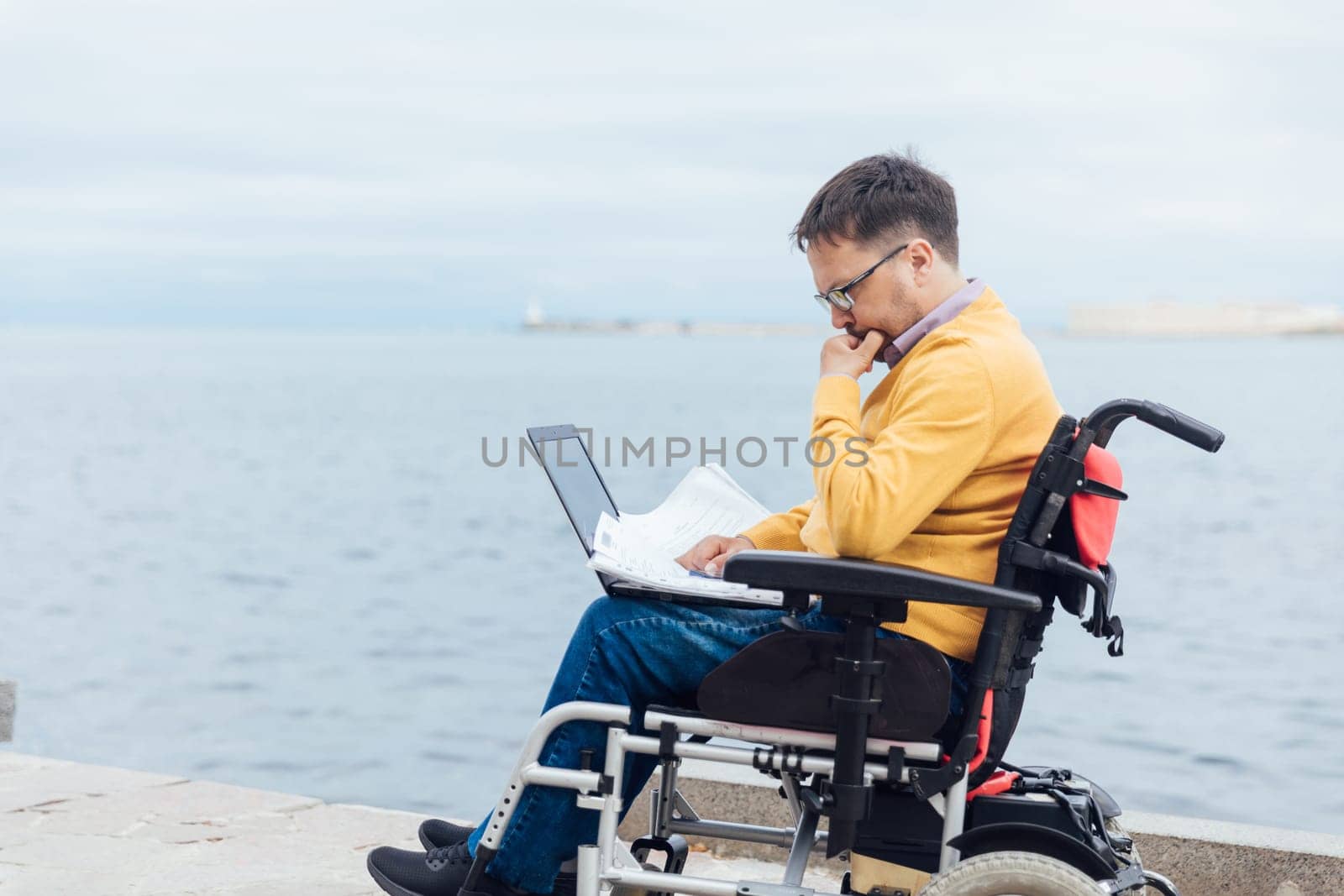 a special person with disabilities by the sea on a walk at work with a laptop