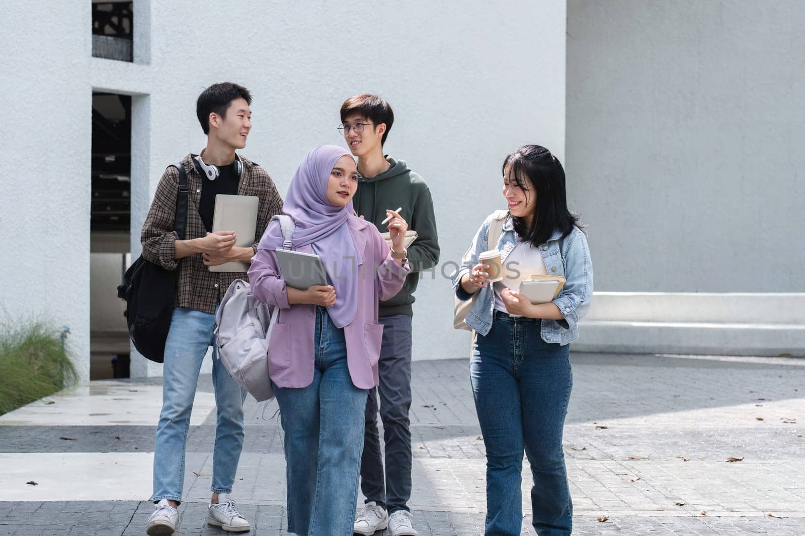 Group of Asian college students use laptops and tablets to study with friends outside of class..