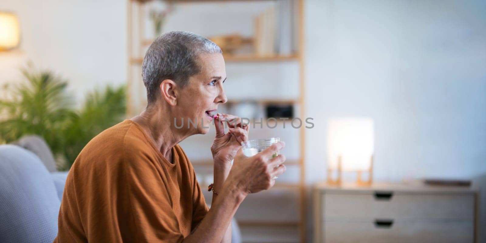 Close up Caucasian senior holding pill in hand with water feeling sick. from headache, painkiller, healthcare, medicine, treatment, therapy, patient, disease illness concept by nateemee