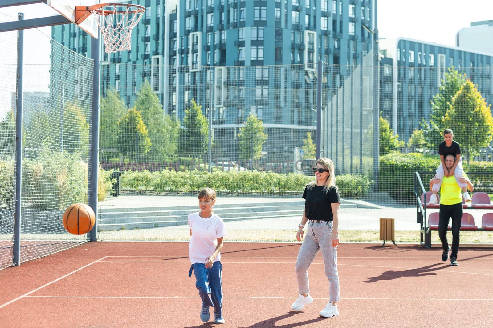 summer holidays, sport and people concept - happy family with ball playing on basketball playground. High quality photo