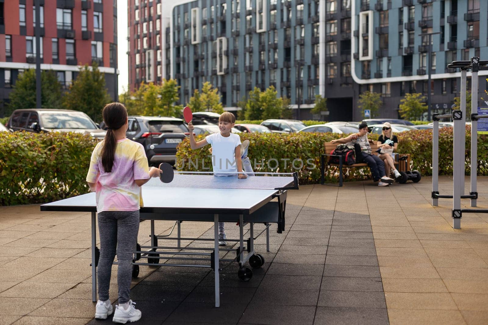 Kid playing table tennis outdoor with family by Andelov13