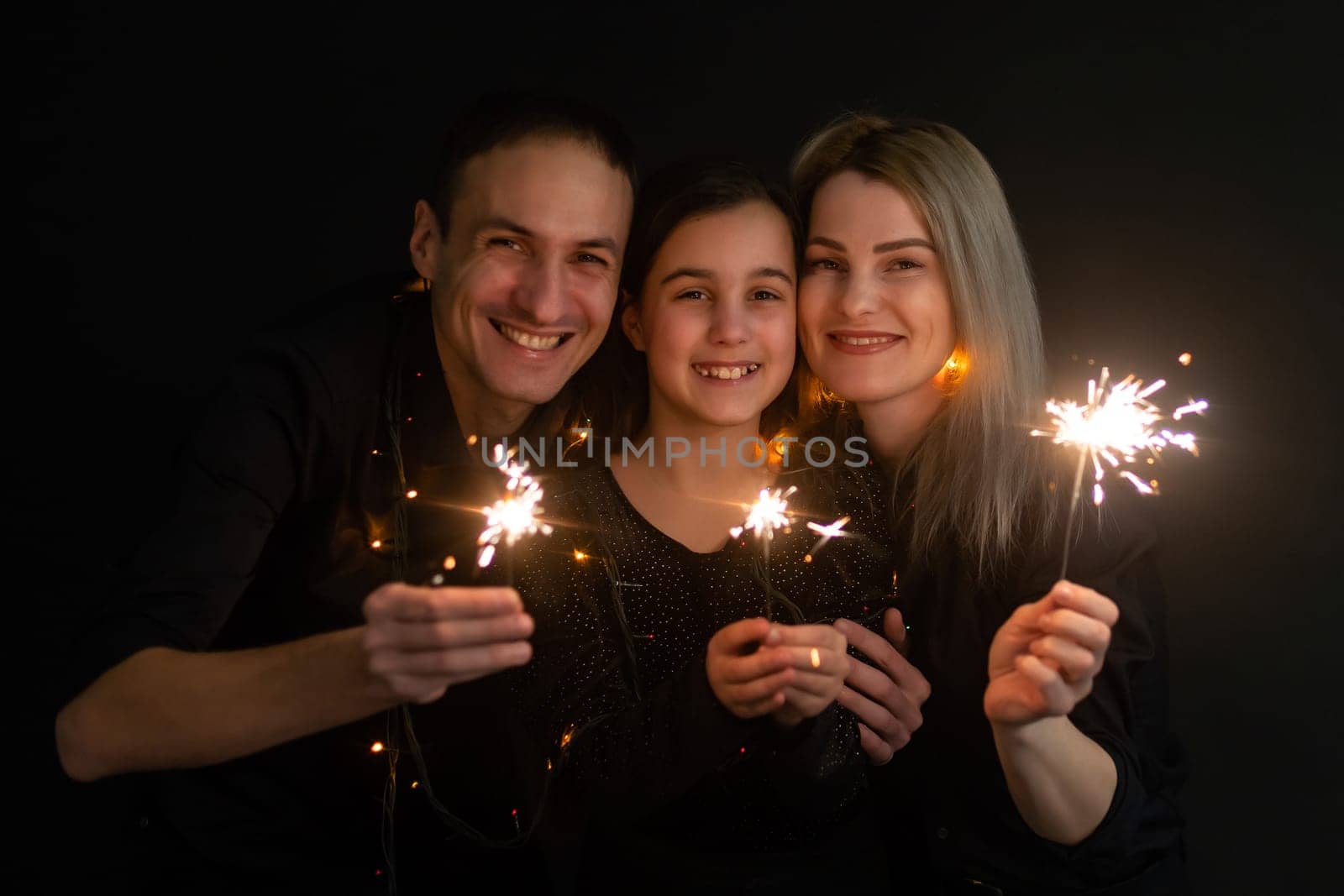 family with sparklers on a black background by Andelov13