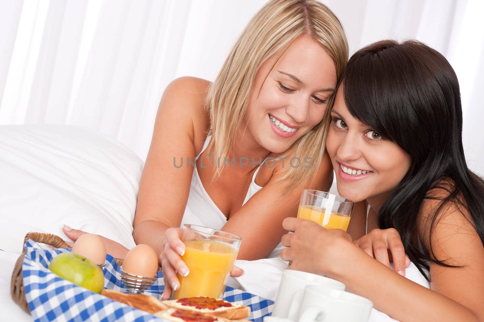 Two girlfrinds having breakfast in white bed