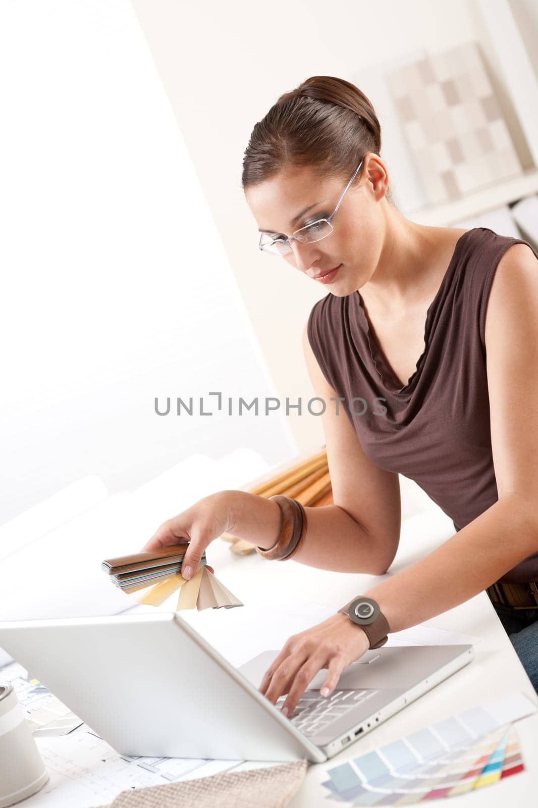 Smiling female designer with color swatch and laptop