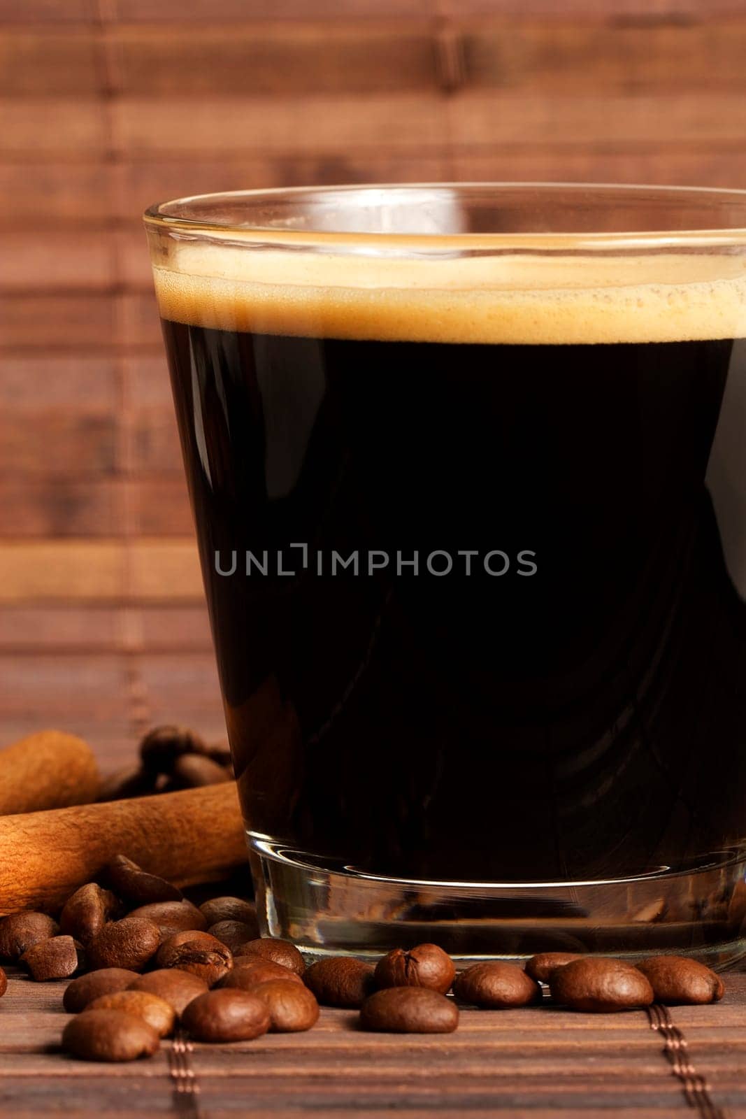 Espresso next to cinnamon and coffee beans