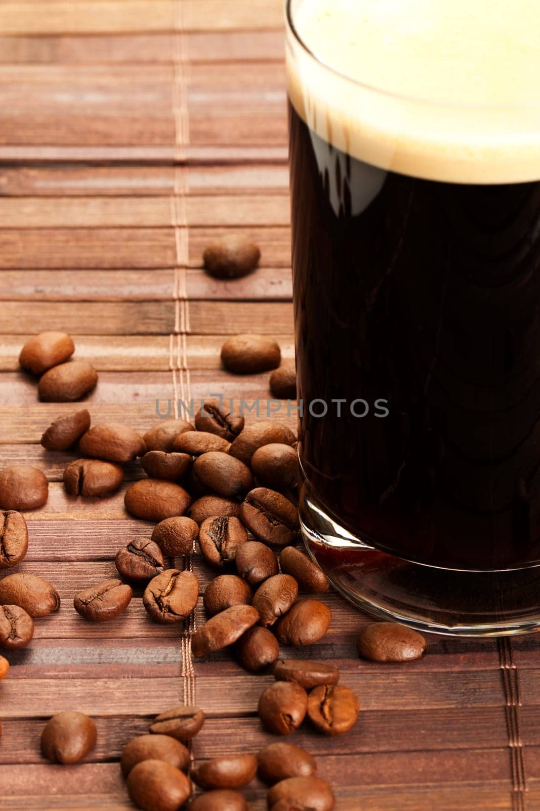 Coffee beans next to a glass of espresso