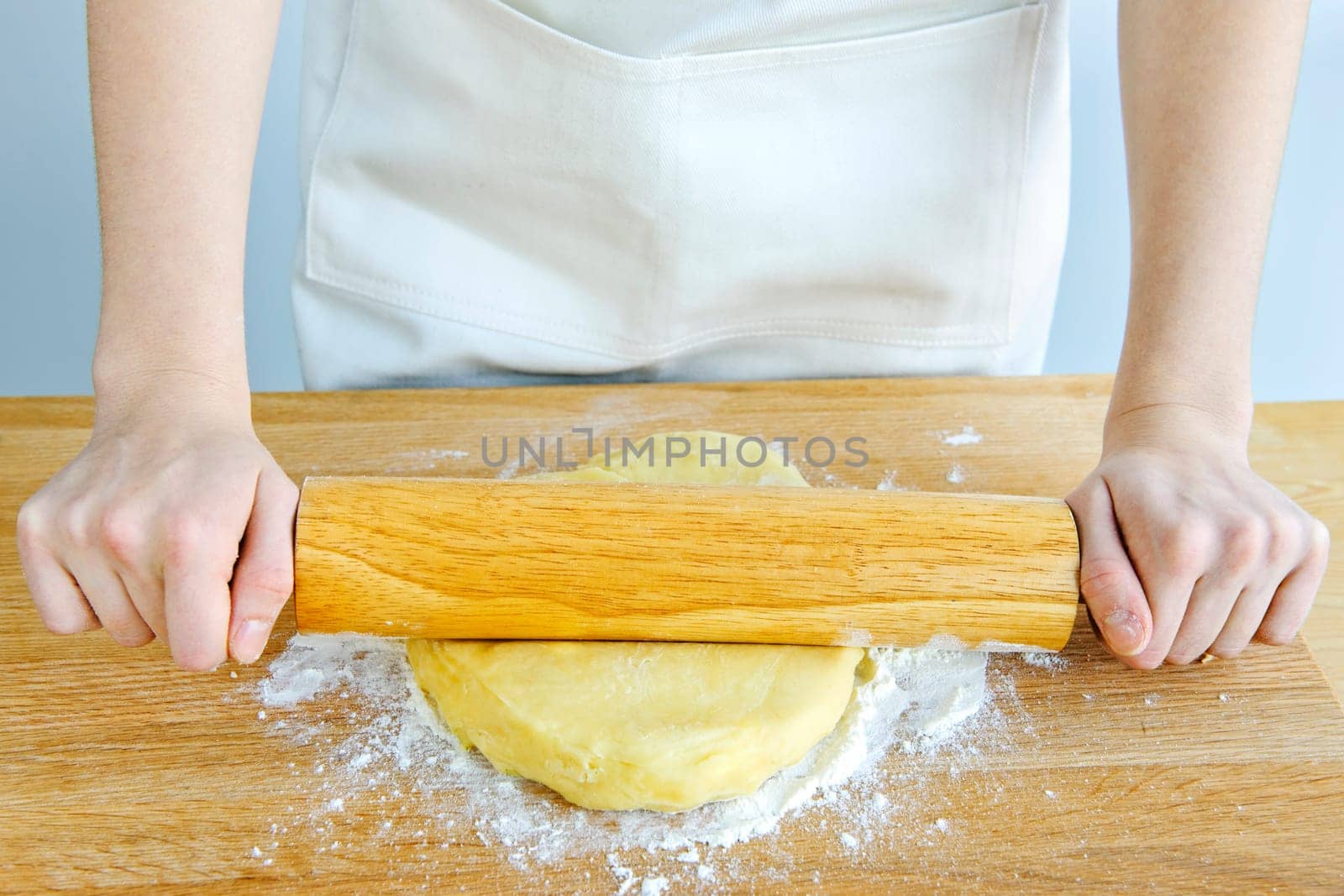 Hands with rolling pin and cookie dough