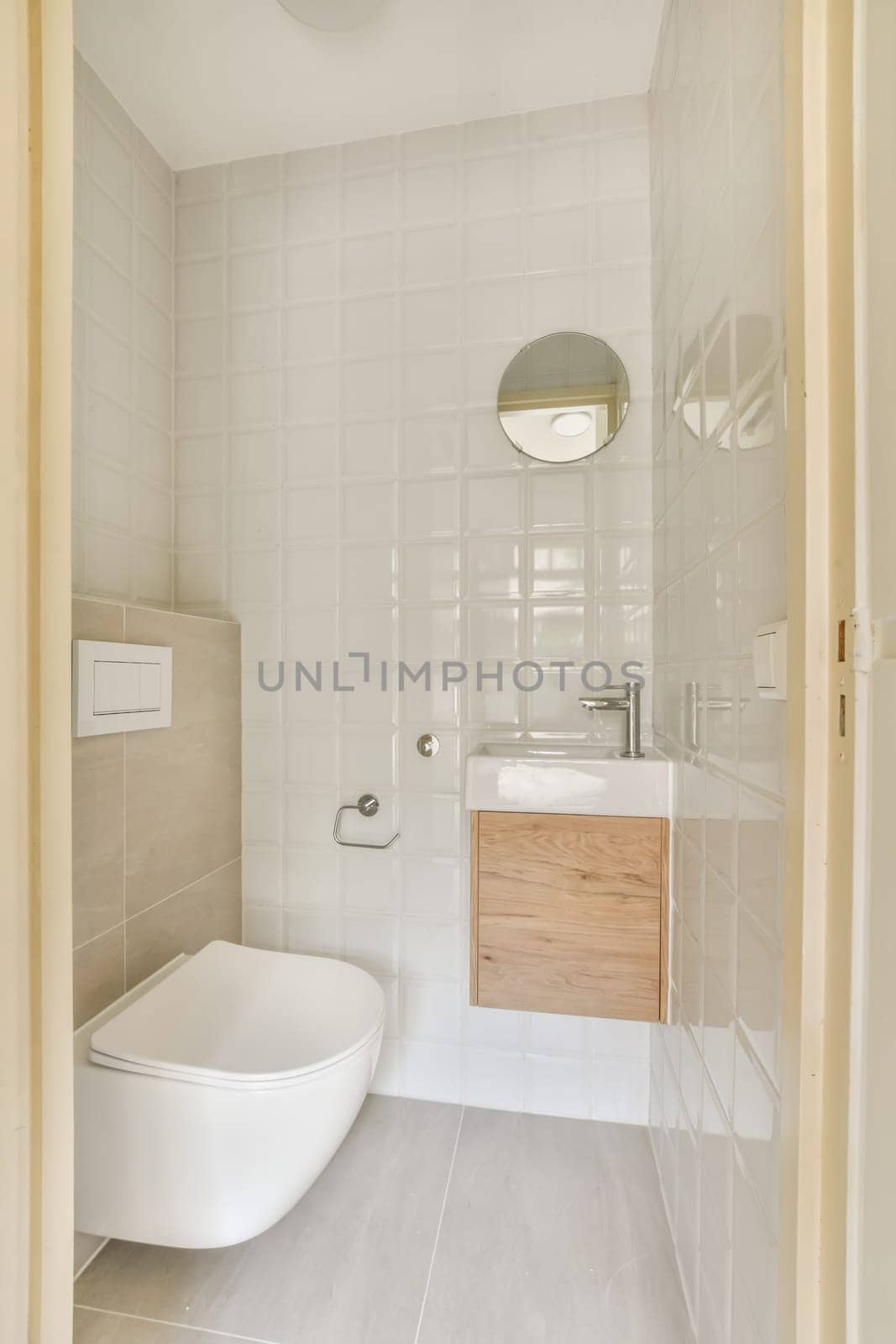 a small bathroom with white tiles and wood cabinet in the corner, as seen from the doorway leading to the toilet