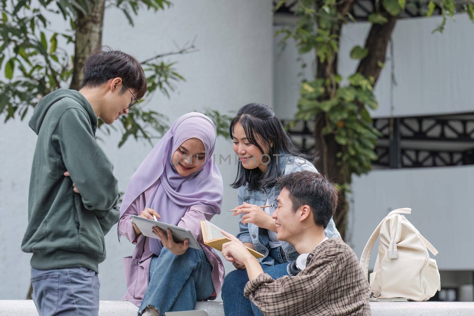 Group of Asian college student reading books and tutoring special class for exam on grass field at outdoors. Happiness and Education learning concept. Back to school concept. Teen and people theme..