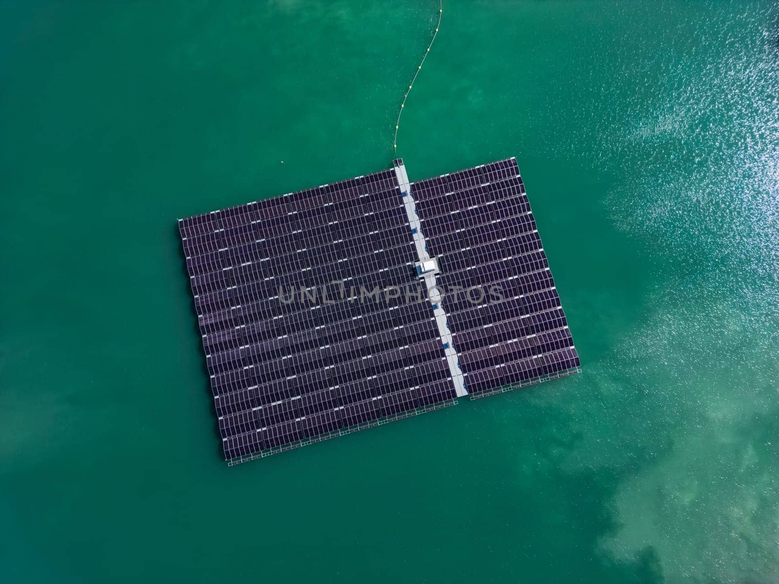 Aerial view of floating solar farm with many solar panels on turquoise lake