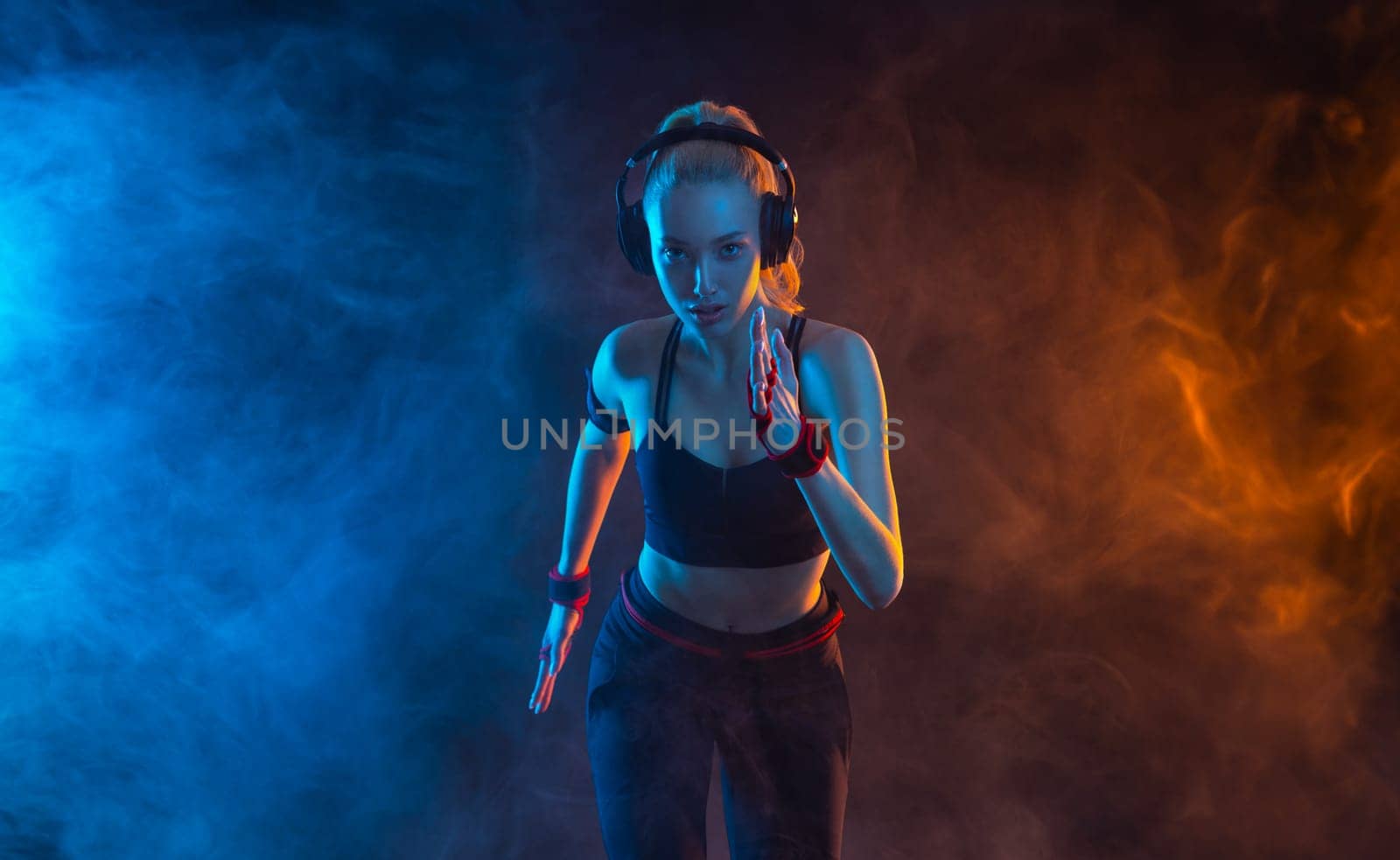 Runner running. Sprinter run. Strong athletic woman running on black background with neon lights wearing in the sportswear. Fitness and sport motivation