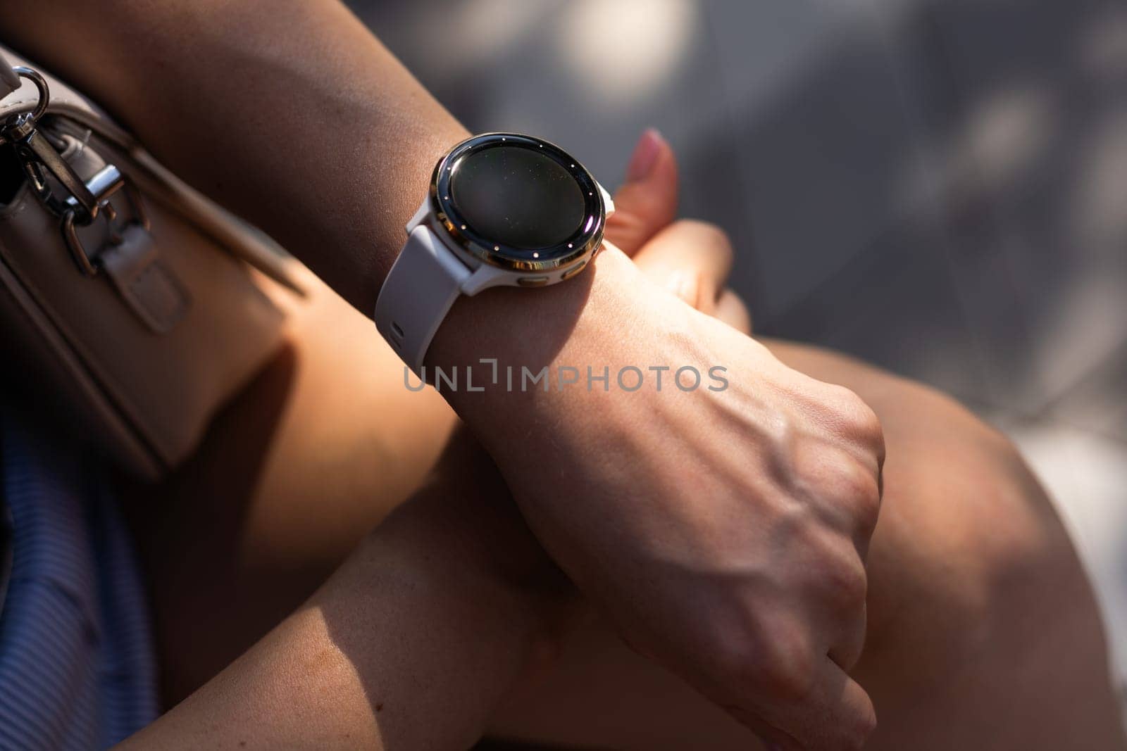 Woman hand wearing a smartwatch and checking active lifestyle and using fitness tracker outdoor on the beach. by Andelov13