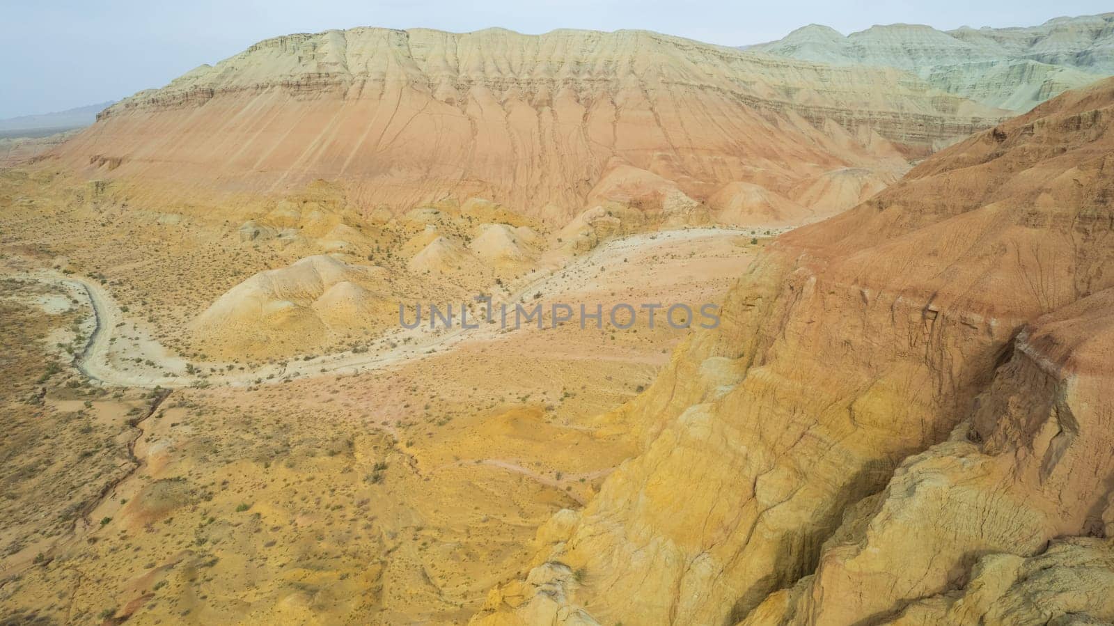 Colorful high mountains and a canyon made of clay. A large gorge with different rocks and different colors. Red, orange, white and yellow flowers of the walls of the rocks. A tourist walks. Aktau