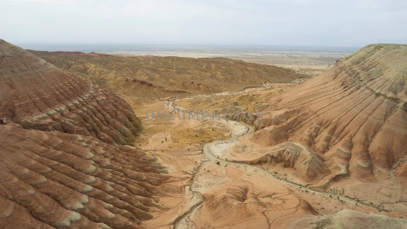 Colorful high mountains and a canyon made of clay. A large gorge with different rocks and different colors. Red, orange, white and yellow flowers of the walls of the rocks. A tourist walks. Aktau