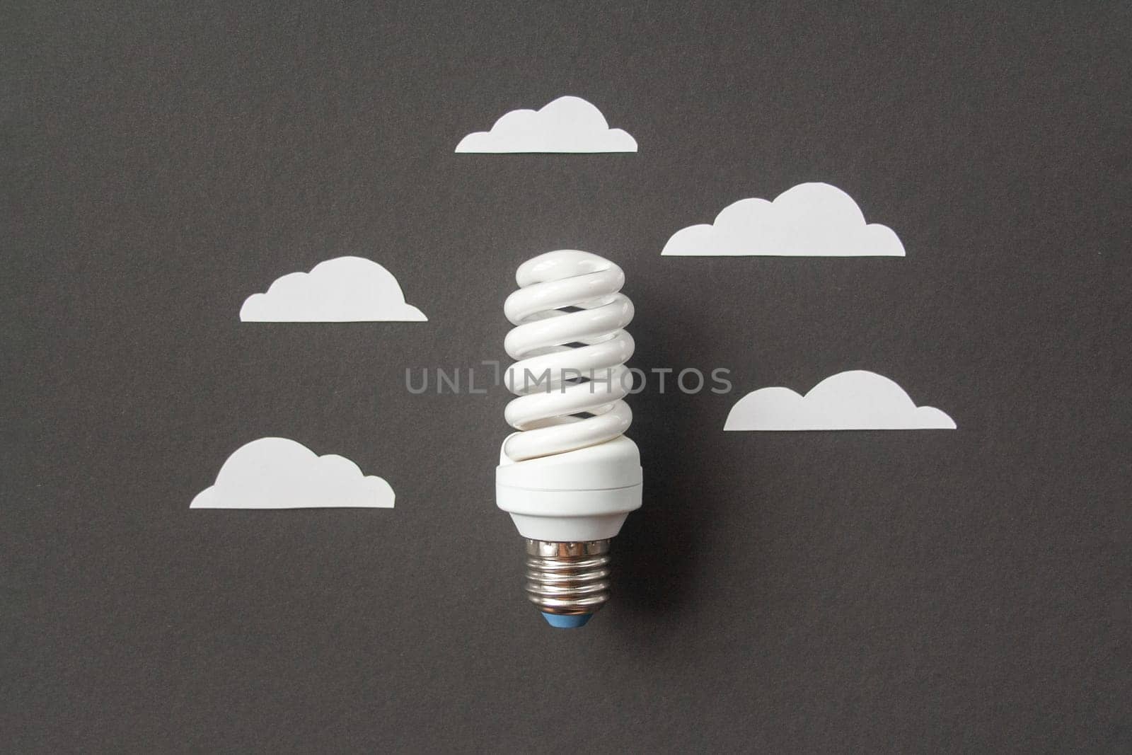 Light bulb with white cut out clouds on black background. Idea concept. Energy and electricity. alternative energy sources. Innovation and thinking out the box symbols. Creativity and inspiration