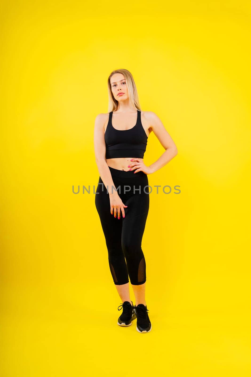 Beautiful young woman dressed in sports uniform, posing in the studio. Healthy lifestyle, sport