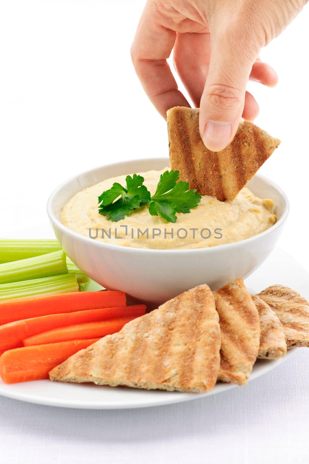 Hand dipping pita in hummus